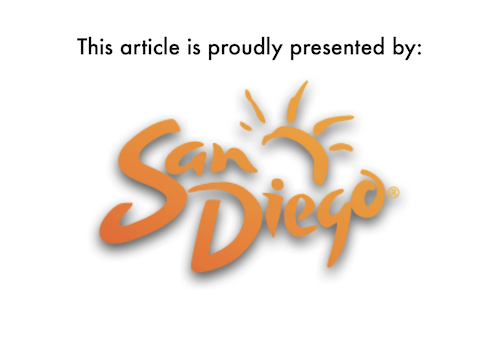 The official logo of the San Diego Tourism Authority, which consists of the stylised words « San Diego » overlayed on top of a stylised version of a setting sun. The logo features a colour gradient from dark orange to light orange.  Above the logo are the words, in black block letters, « This article is proudly presented by: ».